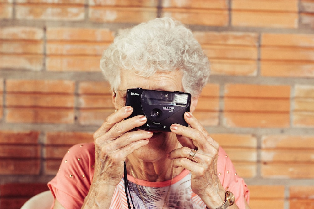 An elderly woman holding a camera