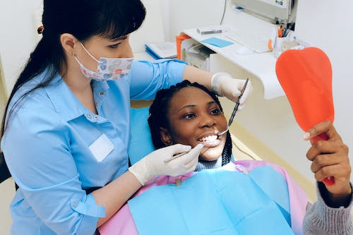 a dentist giving teeth whitening services to a patient